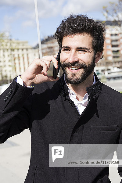 Portrait of smiling young man with full beard on the phone