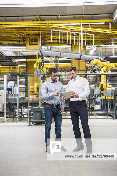 Two men with tablet talking in factory shop floor