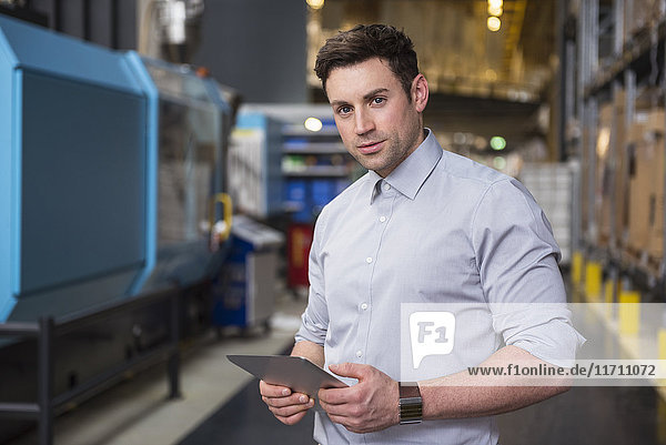 Portrait of man with tablet in factory warehouse