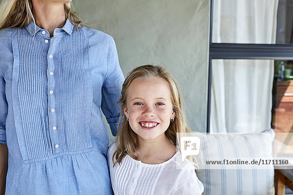 Portrait of smiling little girl beside her mother on terrace