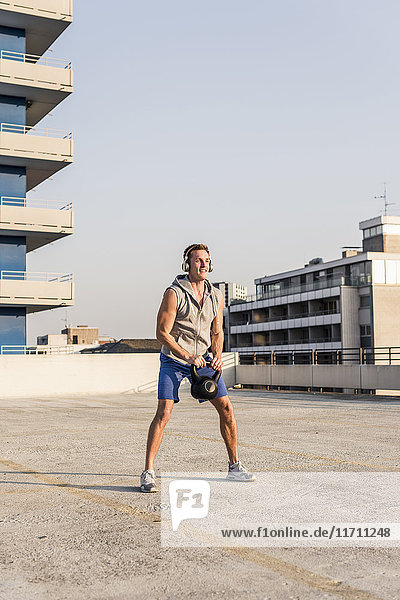 Young man exercising with kettle bell on a rooftop