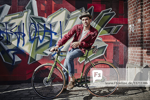 Deutschland  Hamburg  St. Pauli  Mann sitzt auf dem Fahrrad vor Graffiti