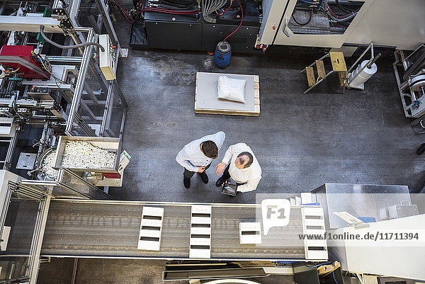 Top view of two men with tablet talking in factory shop floor