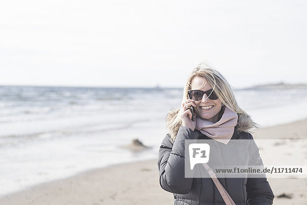 Porträt der glücklichen Frau am Telefon am Strand