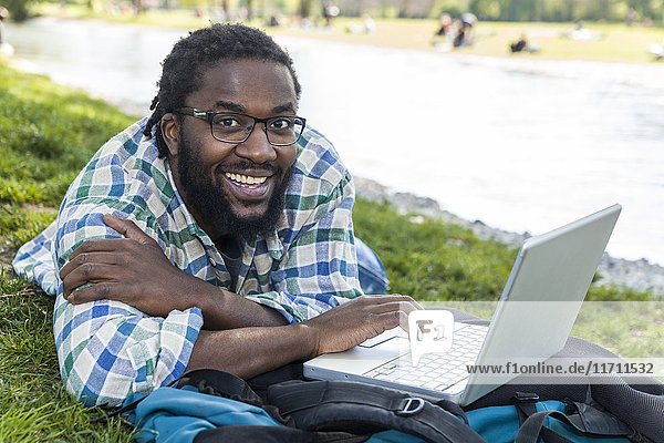 Portrait of smiling man with laptop on a meadow