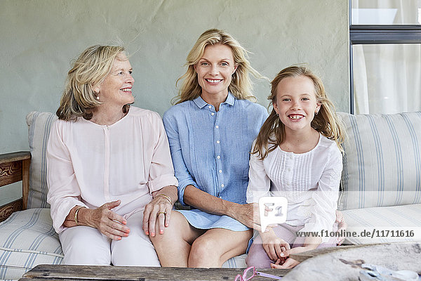 Kleines Mädchen sitzend mit Großmutter und Mutter auf der Terrasse