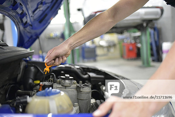 Car mechanic in a workshop checking motor oil