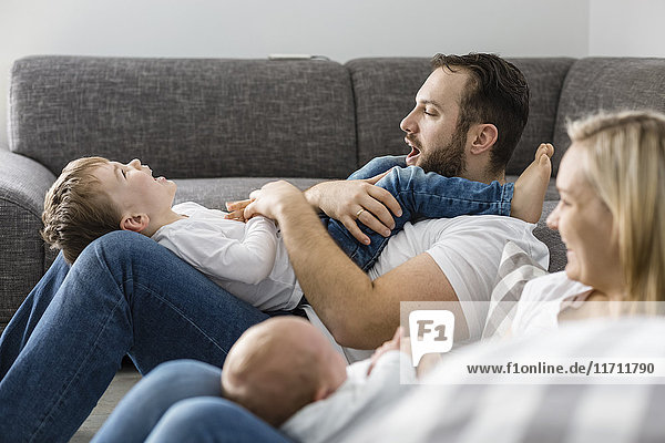 Parents with male newborn and little son having fun at home