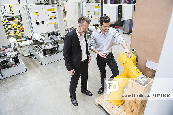 Zwei Männer reden in der Fabrikhalle am Industrieroboter