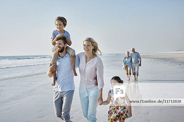 Happy extended family strolling on the beach