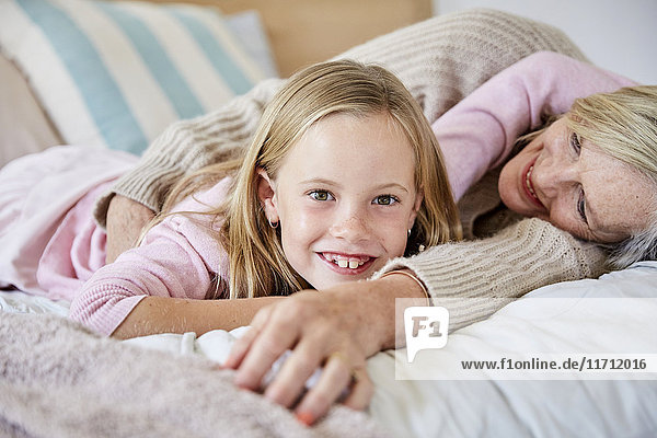 Portrait of happy little girl lying on the bed with her grandmother