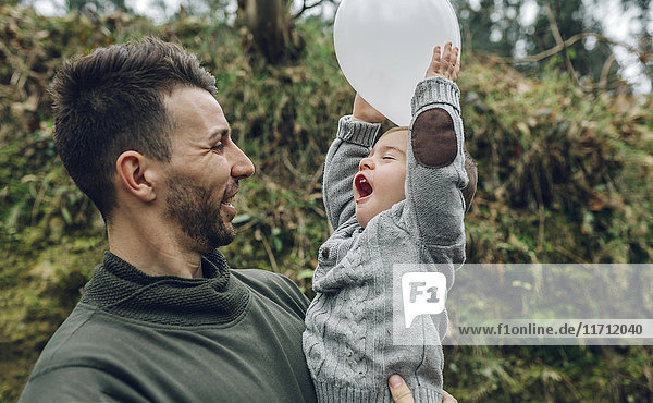 Vater hält kleinen Jungen mit Ballon in der Hand