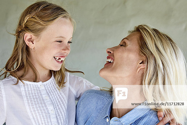 Laughing little girl face to face with her mother