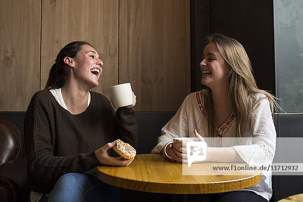 Two laughing friends in a coffee shop