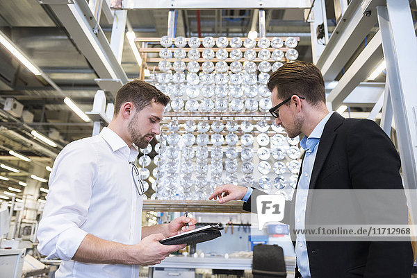 Two men in factory shop floor examining products