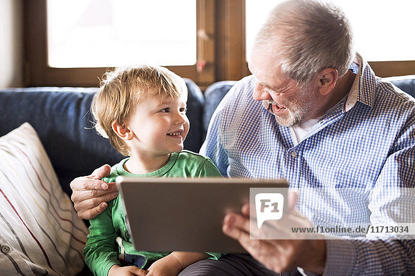 Großvater und Enkel auf der Couch sitzend  mit digitalem Tablett