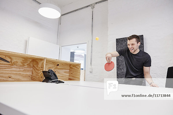 Young businessman playing table tennis in office