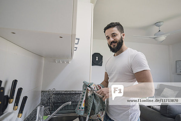 Junger Mann beim Abwaschen in der Küche