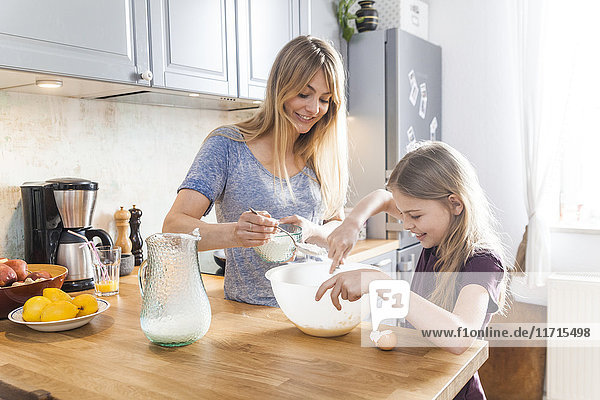 Mother and daughter preparing pancakes in kitchen