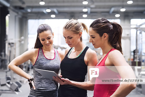 Drei Frauen mit Tablette nach dem Training im Fitnessstudio