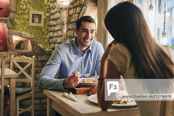 Porträt eines glücklichen jungen Mannes beim Abendessen mit seiner Freundin in einem Restaurant