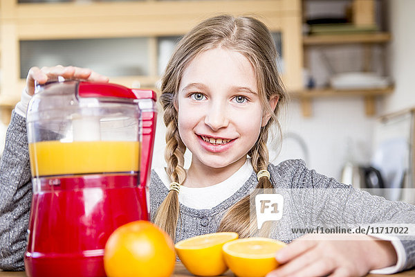 Porträt eines lächelnden Mädchens  das frisch gepressten Orangensaft herstellt.