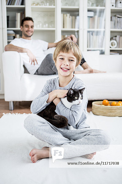 Smiling boy caressing cat at home
