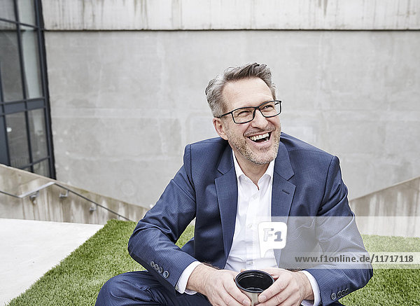 Porträt eines lachenden Geschäftsmannes mit Tasse Kaffee