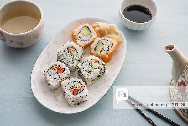 Sushi-Rollen auf einem Teller mit grünem Tee
