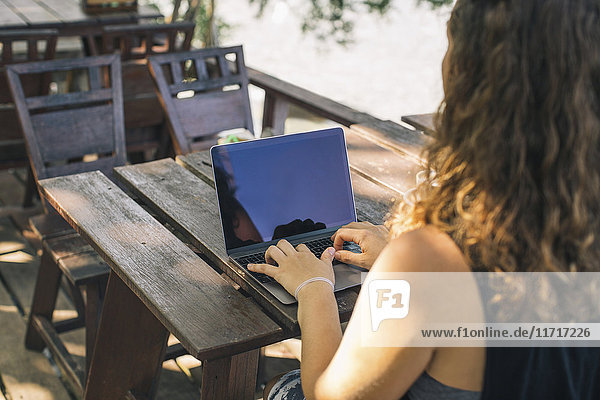 Junge Frau im Freien sitzend  mit Laptop