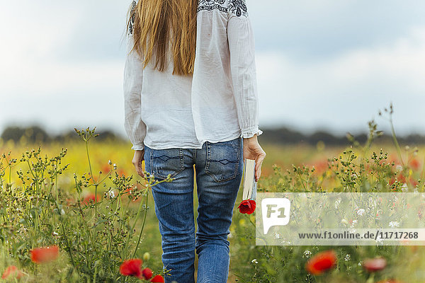 Woman walking in a flower field holding book