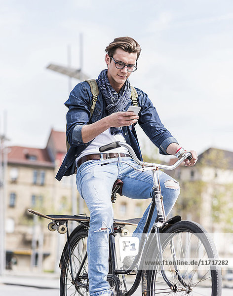 Junger Mann mit Fahrrad in der Stadt per Handy