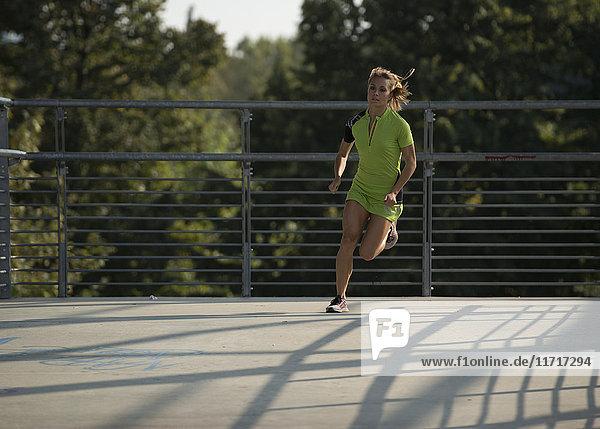 Young woman running on bridge