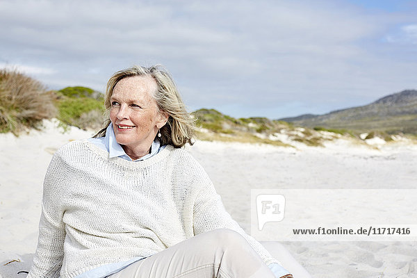 Senior woman sitting on the beach  smiling