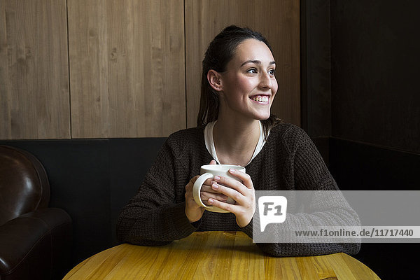 Porträt einer lächelnden Frau mit einer Tasse Kaffee im Coffee Shop