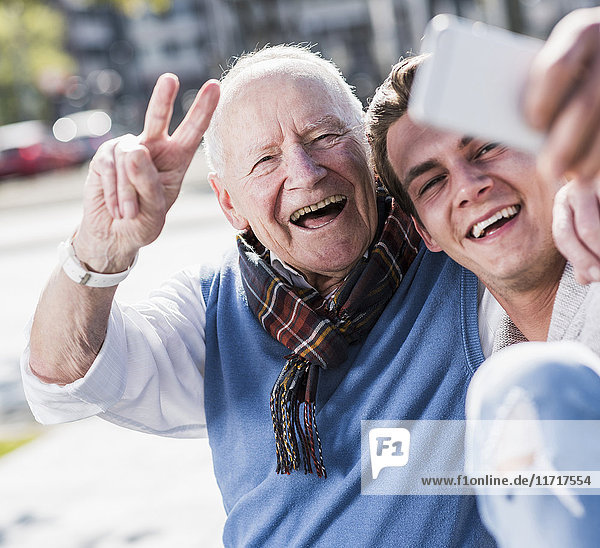 Happy senior man and adult grandson taking a selfie
