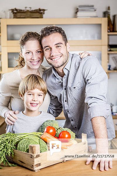 Lächelnde Familie mit Gemüsekiste in der Küche