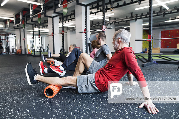 Group of fit seniors in gym using foam rollers