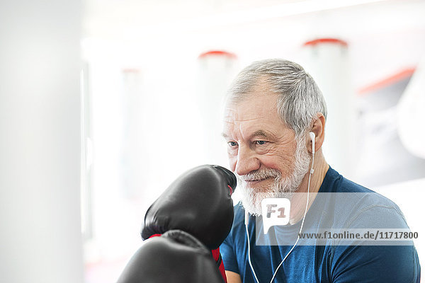 Fit Senior Mann mit Kopfhörern und Boxhandschuhen in der Turnhalle