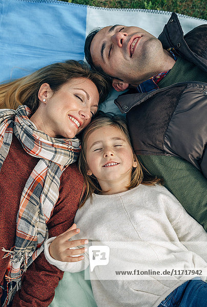 Happy family lying on blanket with closed eyes
