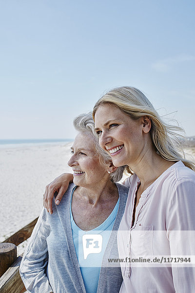Lächelnde Seniorin mit erwachsener Tochter am Strand