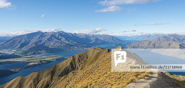 Blick auf Berge und See  Frau springt auf den Gipfelkamm  Roys Peak  Lake Wanaka  Südliche Alpen  Region Otago  Southland  Neuseeland  Ozeanien