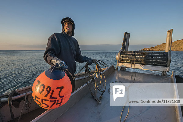 Commercial fishing boat crewman prepares to toss a buoy into the waters of Bristol Bay  Southwest Alaska  USA