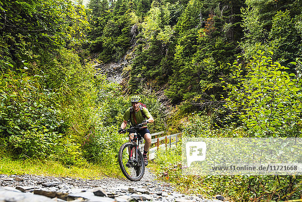 A man riding a mountain bike struggles up a hill on the Johnson Pass Trail in Southcentral Alaska  USA