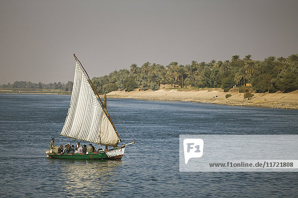 Menschen in einer alten Feluke  die auf dem Nil segeln; Ägypten'.