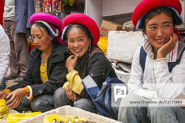 'Three young women sit at the market selling mushrooms; Shangrila Yunnan province China'