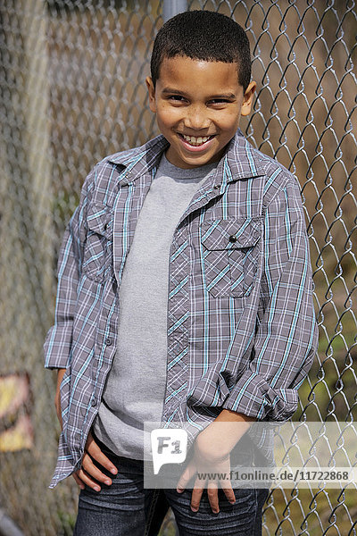 'Portrait of a young boy standing against a chain link fence; Oregon  United States of America'