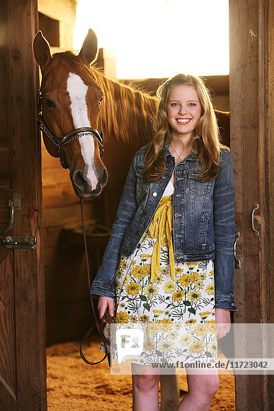 'Portrait of a girl standing in a stable with her horse; Oregon  United States of America'