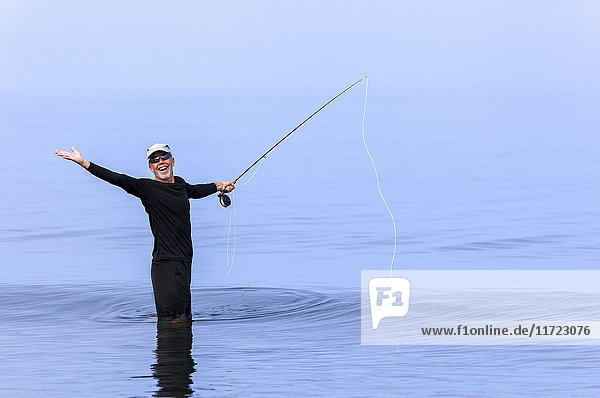 Ein Mann beim Fliegenfischen  der mit aufgeregtem Gesichtsausdruck posiert; Port McNeill  British Columbia  Kanada