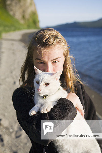 Ein Mädchen hält ihre weiße Katze am Strand; False Pass  Alaska  Vereinigte Staaten von Amerika'.